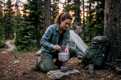 Backpacker cooking with portable stove at dusk