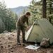 Camper setting up tent in remote forest clearing